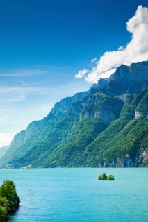 Sunny view over Lake Walen with the small chive island in the turquoise water and mountain range