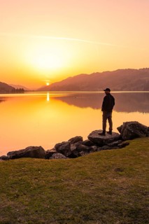 Lonely person standing at the lakeside and watching the sunset, Großer Alpsee, Immenstadt im