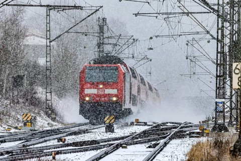 RegionalExpress RE on the road through a winter landscape in snowfall. A train on the line in the