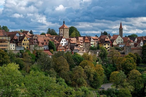 Walls and buildings of the old town of Rothenburg ob der Tauber above the autumnal colourful forest