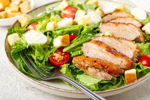 Caesar salad, with duck breast, on a light plate, on a light background, homemade, no people