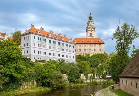 View of the Ceský Krumlov Castle with tower, colorful facade buildings, Vltava River, and greenery,
