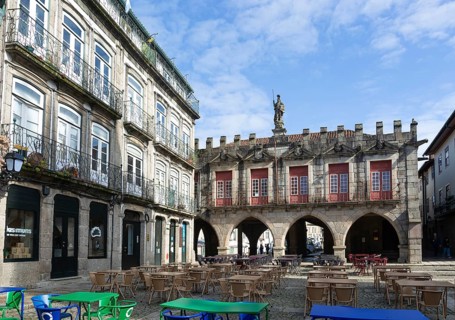 Tables and chairs, historic buildings in Largo da Oliveira square, city of Guimaraes, northern
