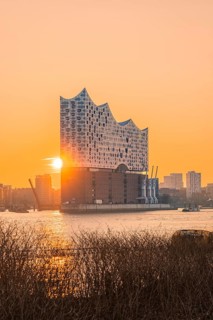 Sunlight breaks out behind the Elbphilharmonie over the water, Hamburg, Germany