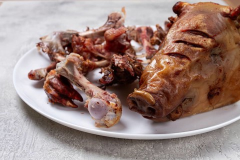 Roast pork head, with remnants of bones and meat, on a white platter, no people, close-up