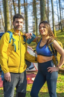 Hikers posing happily near their campsite in the woods, taking a well deserved break from their
