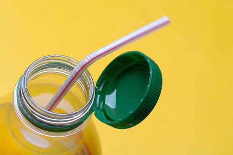 Orange juice in plastic bottle with cap and straw