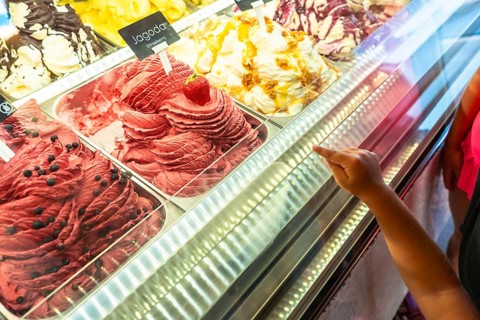 Kid pointing at strawberry ice cream flavor in a gelateria in piran, slovenia, during summer