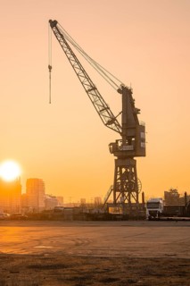 Industrial crane at the harbour at sunrise with the city in the background, Hamburg, Germany