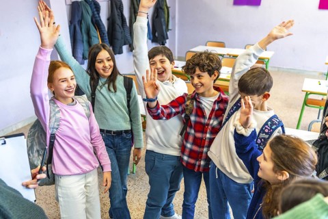 Group of cheerful elementary school students raising hands and actively participating during a
