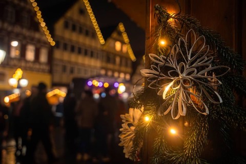 Close-up of a Christmas decoration at night with illuminated traditional houses behind, Christmas