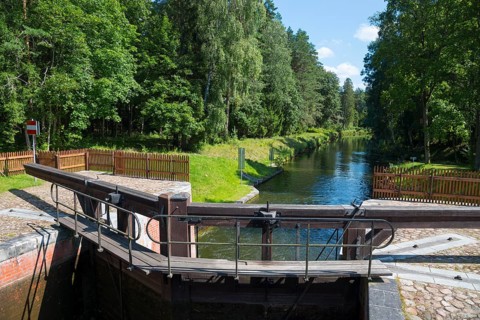 Wooden mechanism of the lock on the waterway through a green forest area, Sluza Perkuc, Perkuc