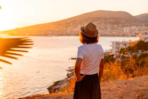 Tourist woman at Sarande or Saranda sunset in Albanian riviera enjoying summer vacation, Albania