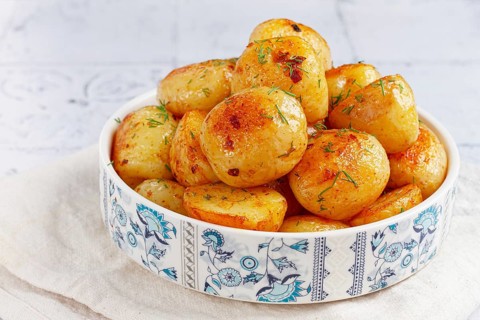 Baked new potatoes, with butter and dill, on a white plate, at home, no people