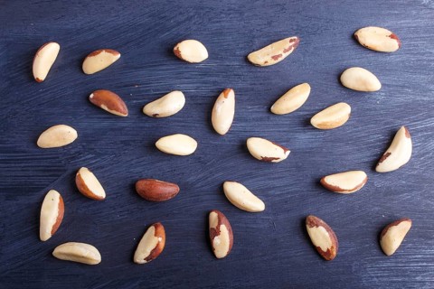 Pattern and texture made from Brazil nuts on black wooden background, flat lay. top view