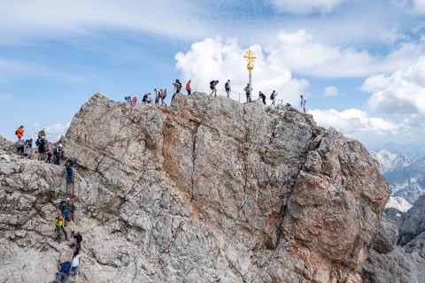 Tourists queue up for the summit of the Zugspitze, summit with golden summit cross, overtourism,