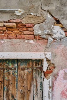 Old crumbling wall and window frame with weathered wood of an old shutter, Burano, Venice Italy