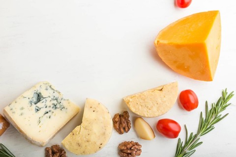 Set of different types of cheese with rosemary and tomatoes on a white wooden background. Top view,