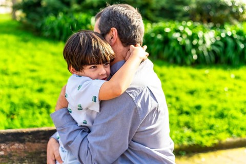 Grandfather and grandson sharing a tender hug in a vibrant park setting, enjoying quality time
