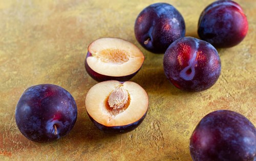 Plums scattered on the table, fresh, top view, yellow-orange background, no people