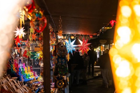 Various colourful stars hanging in a festively illuminated market stall at night, Christmas market
