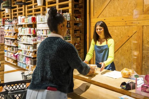 Friendly saleswoman serving a customer buying organic products in a zero waste store or supermarket