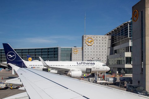 Lufthansa aircraft and airport building with modern terminals under a clear sky, Frankfurt am Main,