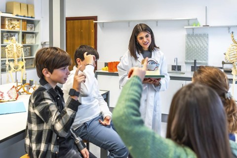 Science teacher explaining human eye anatomy to high school students using a model during a biology
