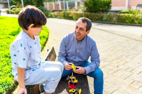 Grandfather and grandson enjoying quality time together, playing with toy trucks in a sunny park,