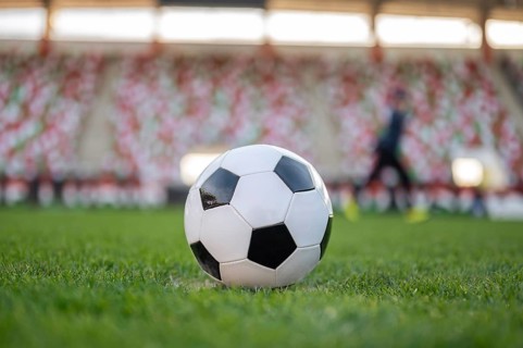 Soccer ball on the field and silhouette of player in the backgrond