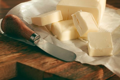 Butter briquette, on wrapping paper, wooden chopping board and butter knife, breakfast, rustic