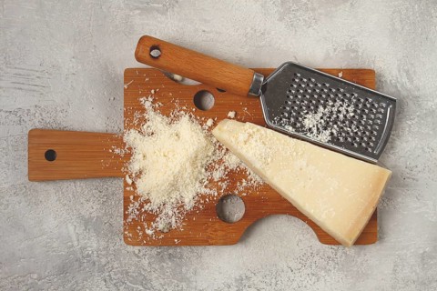 Freshly sliced and grated cheese, parmesan cheese, Gran gusto. Grana padano. on a wooden chopping
