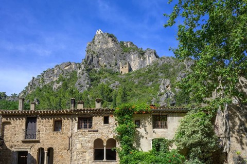 View from Place de Liberte over old stone house up to ruins in the rocks, Saint-Guilhem-le-Désert,