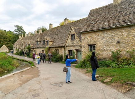 Tourists visiting famous Cotswold buildings at Arlington Row, Bibury, Gloucestershire, England, UK
