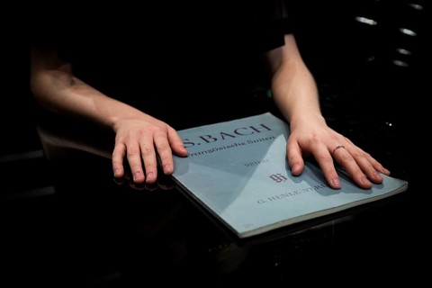 Hands of a young pianist resting on sheet music by Johann Sebastian Bach, Steinway & Sons grand