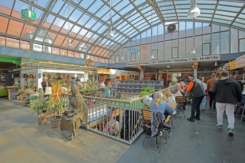 Interior view of the historic market hall with restaurant, market stalls and visitors, shops,