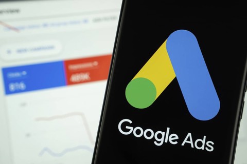 Google Ads logo is displayed on a smartphone screen, with a stock graph webpage visible on a