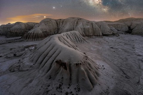 A serene nighttime scene captures Utah's textured landscape under a starlit sky, highlighted by the