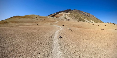 Hiking trail and rock formations, volcanic landscape in El Teide National Park, behind it the Pico