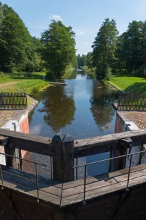 A wooden river lock leads into a forest that lines the water, Tartak Lock, Augustow Canal,