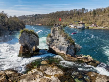 Aerial view of the Rhine Falls at low water in spring, with tourists on the viewing platform, on