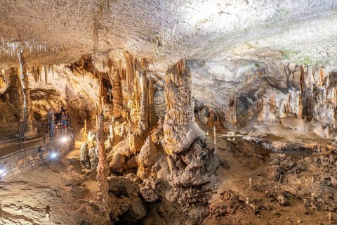 Tourists admiring the magnificent formations of stalactites and stalagmites inside postojna cave, a