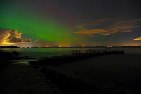 Northern Lights over a dark fjord, the shore in the background, starry sky, Tönsberg, Oslofjord,