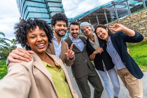 Multi-ethnic business colleagues gesturing success while taking selfie together outdoors in the