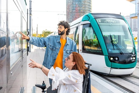 Young man assists a woman in a wheelchair, pointing at the tram schedule at a modern station,