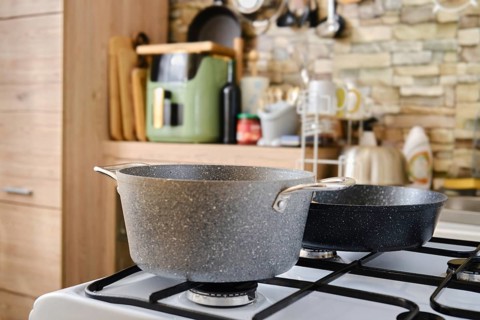 A spacious kitchen features a gray pot and a black pan on a gas stove, showcasing a blend of modern