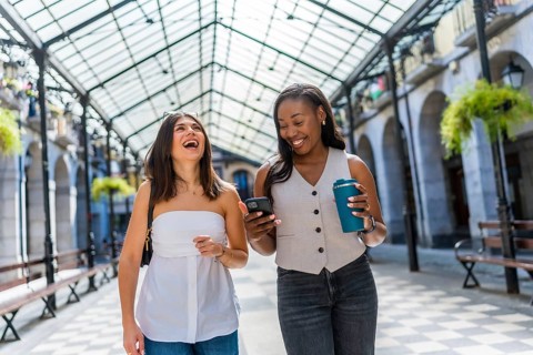 Two happy female friends are enjoying their free time together, strolling through a charming