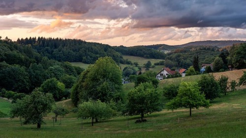 The village of Lampenhain in the Odenwald, landscape with trees, meadows, forest and hills. Sunset.