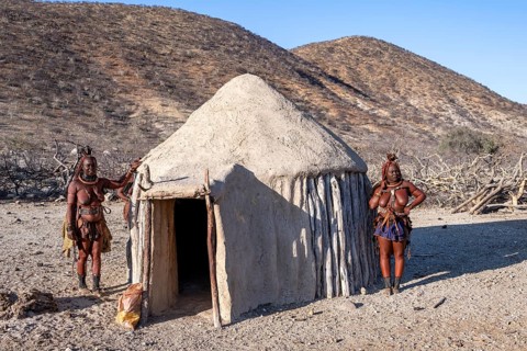 Married Himba woman leaning against a traditional mud house, traditional Himba village, Kaokoveld,