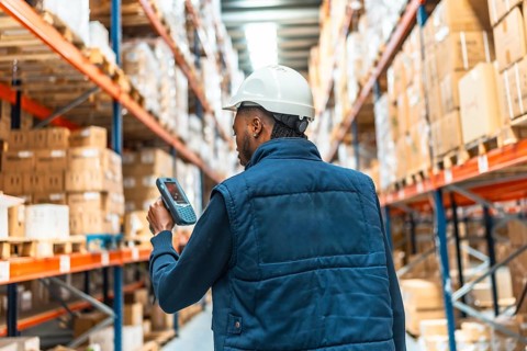 Rear view of an african young worker using scanner to do inventory in a large distribution